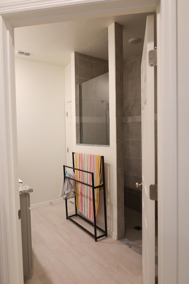 bathroom featuring vanity, wood-type flooring, and tiled shower