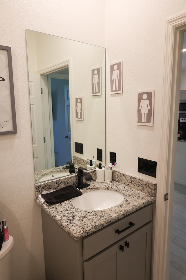 bathroom featuring vanity, hardwood / wood-style flooring, and toilet