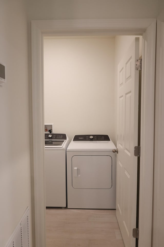 laundry area featuring light hardwood / wood-style flooring and washing machine and clothes dryer