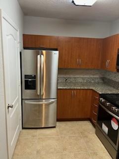 136 SW Peacock Blvd Unit 19-204, Port Saint Lucie, FL 34986 - kitchen with stainless steel appliances, brown cabinets, and dark countertops
