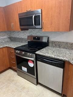 kitchen with light stone countertops, decorative backsplash, and appliances with stainless steel finishes