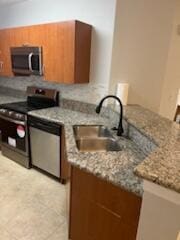136 SW Peacock Blvd Unit 19-204, Port Saint Lucie, FL 34986 - kitchen featuring stainless steel appliances, a sink, brown cabinets, and a peninsula