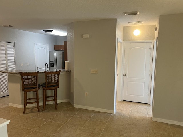 136 SW Peacock Blvd Unit 19-204, Port Saint Lucie, FL 34986 - kitchen featuring stainless steel refrigerator with ice dispenser, a breakfast bar, and light tile patterned flooring