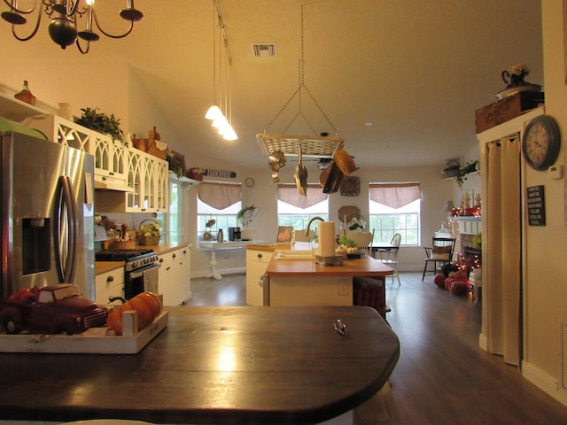 kitchen featuring a kitchen island, hanging light fixtures, stainless steel appliances, wooden counters, and dark hardwood / wood-style floors