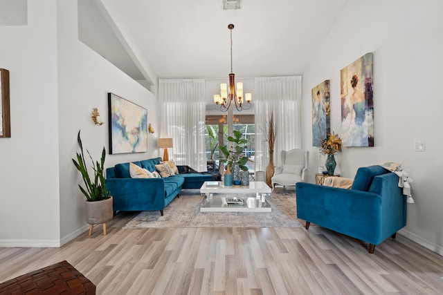 living room featuring lofted ceiling, light hardwood / wood-style floors, and an inviting chandelier