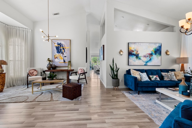 living room featuring a notable chandelier, high vaulted ceiling, and light hardwood / wood-style floors