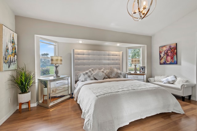 bedroom featuring lofted ceiling, hardwood / wood-style floors, and a notable chandelier