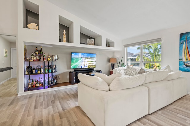 living room featuring lofted ceiling, hardwood / wood-style flooring, and bar