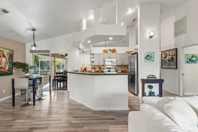 kitchen with appliances with stainless steel finishes, pendant lighting, gray cabinets, high vaulted ceiling, and light hardwood / wood-style flooring