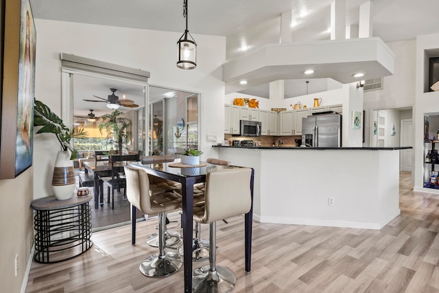 dining room featuring light hardwood / wood-style flooring, high vaulted ceiling, and ceiling fan