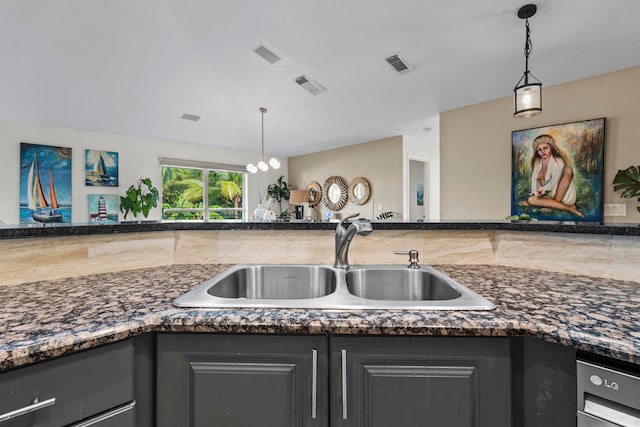 kitchen featuring dark stone counters, sink, a chandelier, and hanging light fixtures