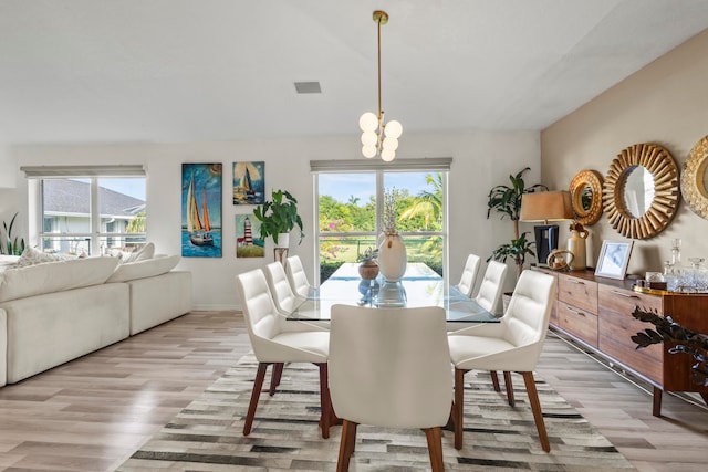 dining area featuring a chandelier, light wood-type flooring, and a healthy amount of sunlight