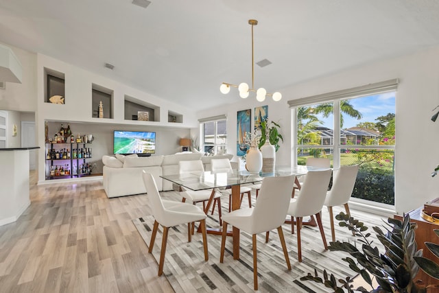 dining room with an inviting chandelier, light hardwood / wood-style flooring, and lofted ceiling