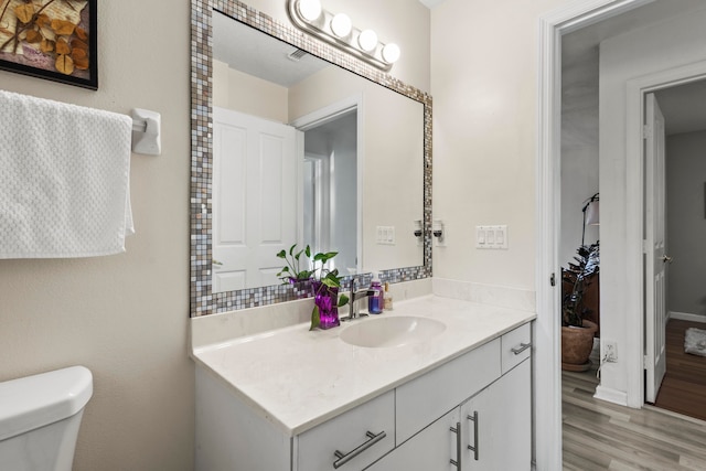 bathroom featuring vanity, toilet, and hardwood / wood-style flooring