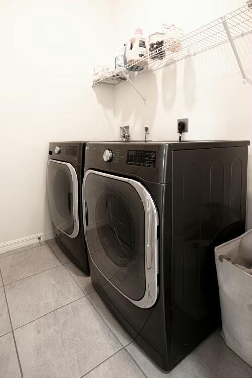 laundry area with washer and clothes dryer and light tile patterned floors