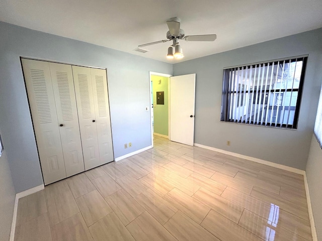 unfurnished bedroom with ceiling fan, multiple windows, electric panel, and a closet