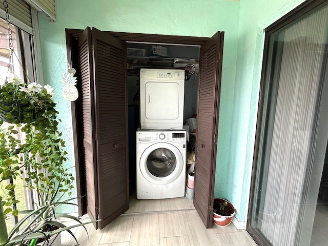 clothes washing area featuring a healthy amount of sunlight and stacked washer and clothes dryer