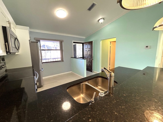 kitchen with sink, stainless steel appliances, lofted ceiling, white cabinets, and ornamental molding