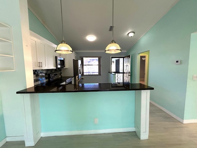 kitchen with white cabinets, stainless steel appliances, hanging light fixtures, and lofted ceiling