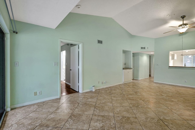 tiled empty room with ceiling fan, high vaulted ceiling, and a textured ceiling