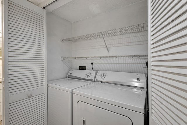 washroom with a textured ceiling and separate washer and dryer