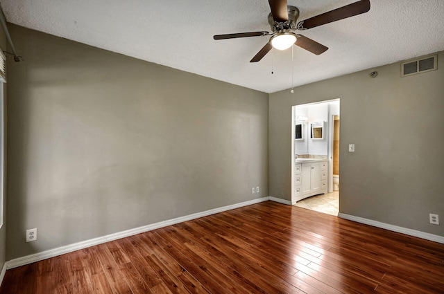 unfurnished bedroom featuring ensuite bath, a textured ceiling, light wood-type flooring, and ceiling fan