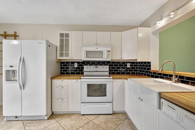 kitchen with white appliances, wood counters, light tile patterned floors, and white cabinets