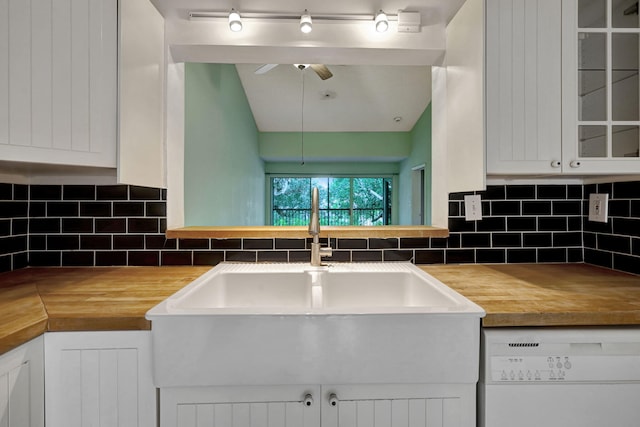 kitchen featuring sink, backsplash, butcher block countertops, white dishwasher, and white cabinetry