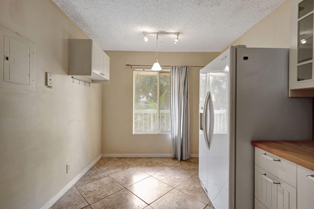 kitchen featuring white cabinets, light tile patterned floors, white fridge with ice dispenser, wood counters, and decorative light fixtures