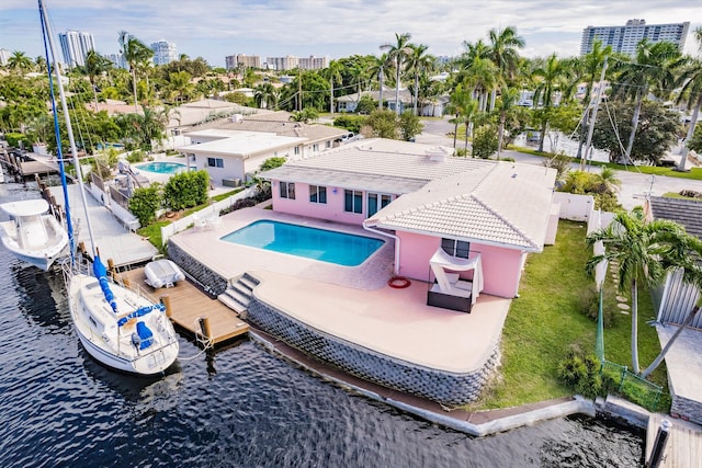 view of pool with a lawn, a patio area, a water view, and a boat dock