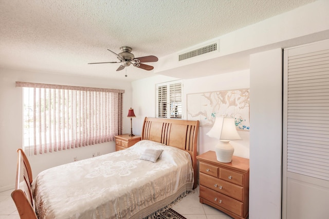 tiled bedroom featuring ceiling fan and a textured ceiling