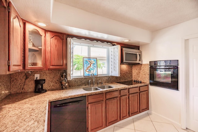 kitchen featuring black appliances, sink, light tile patterned floors, a textured ceiling, and tasteful backsplash