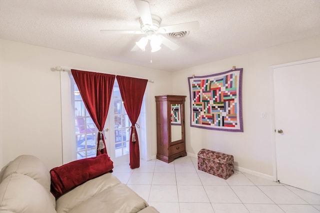 sitting room featuring ceiling fan, light tile patterned flooring, and a textured ceiling