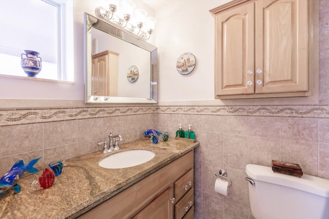 bathroom with vanity, toilet, and tile walls