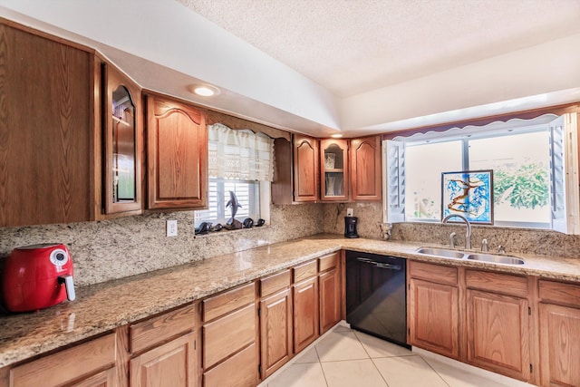 kitchen with dishwasher, sink, light tile patterned floors, a textured ceiling, and light stone counters