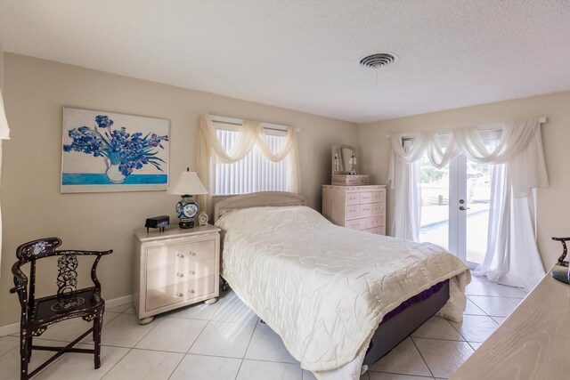 tiled bedroom with access to outside, multiple windows, french doors, and a textured ceiling