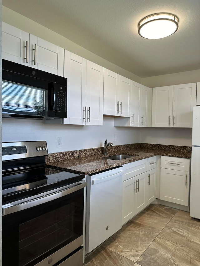 kitchen with a textured ceiling, white cabinetry, dark stone countertops, sink, and white appliances