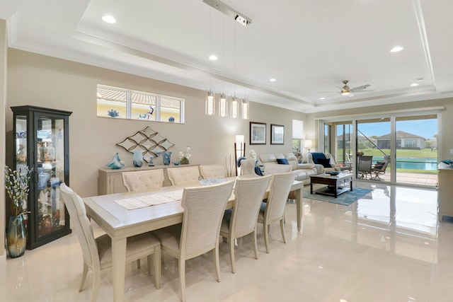 dining area with ornamental molding, light tile patterned flooring, a raised ceiling, a water view, and ceiling fan