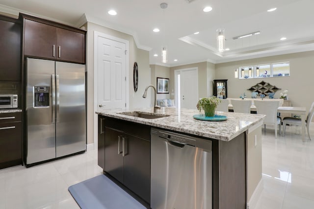 kitchen featuring dark brown cabinets, hanging light fixtures, appliances with stainless steel finishes, a kitchen island with sink, and sink