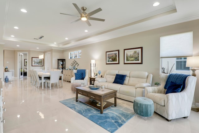 tiled living room featuring ornamental molding, a tray ceiling, and ceiling fan