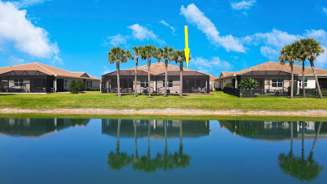 view of swimming pool featuring a yard, a water view, and glass enclosure