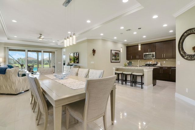 tiled dining space with ornamental molding, a tray ceiling, and ceiling fan