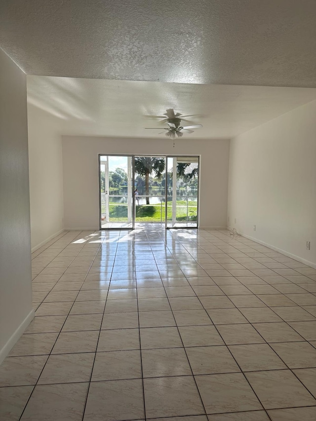 unfurnished room featuring a textured ceiling, light tile patterned flooring, and ceiling fan