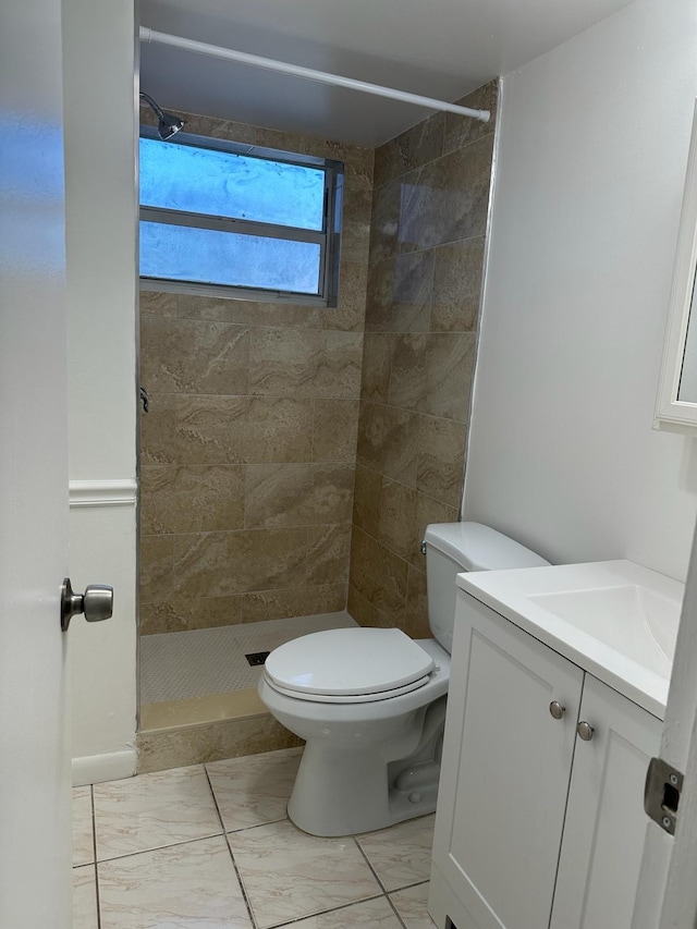 bathroom featuring toilet, vanity, and tiled shower