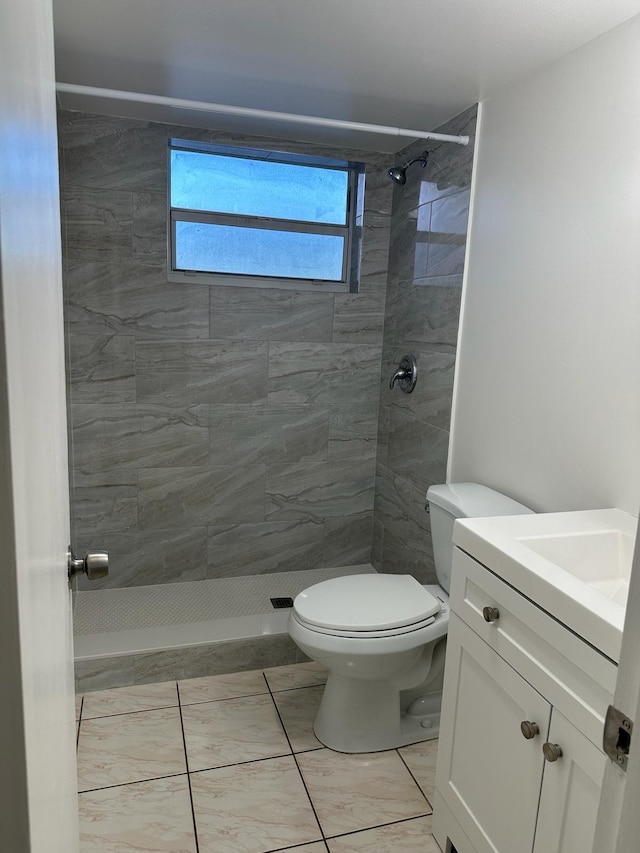 bathroom with vanity, toilet, and a tile shower