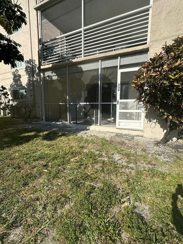 back of property featuring a lawn and a sunroom