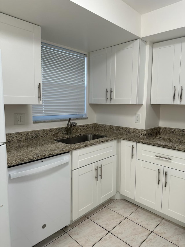 kitchen with sink, white dishwasher, white cabinetry, dark stone counters, and light tile patterned floors