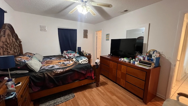 bedroom with light hardwood / wood-style floors, ceiling fan, and a textured ceiling