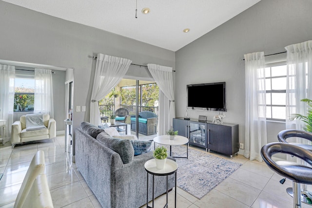 living room with high vaulted ceiling, a healthy amount of sunlight, and light tile patterned floors