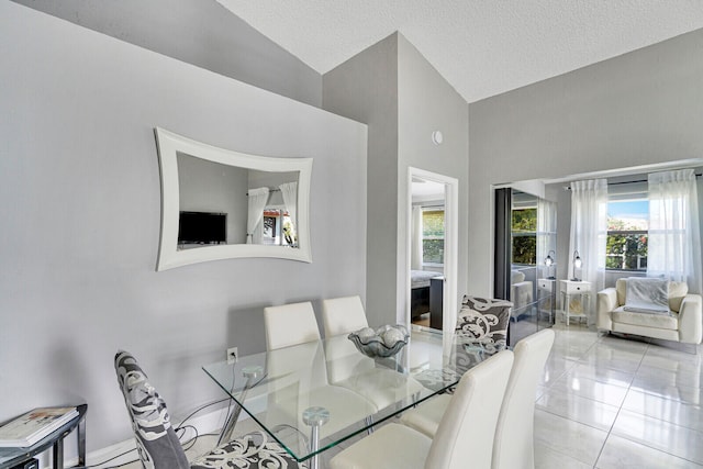 dining space with a textured ceiling, high vaulted ceiling, and light tile patterned floors